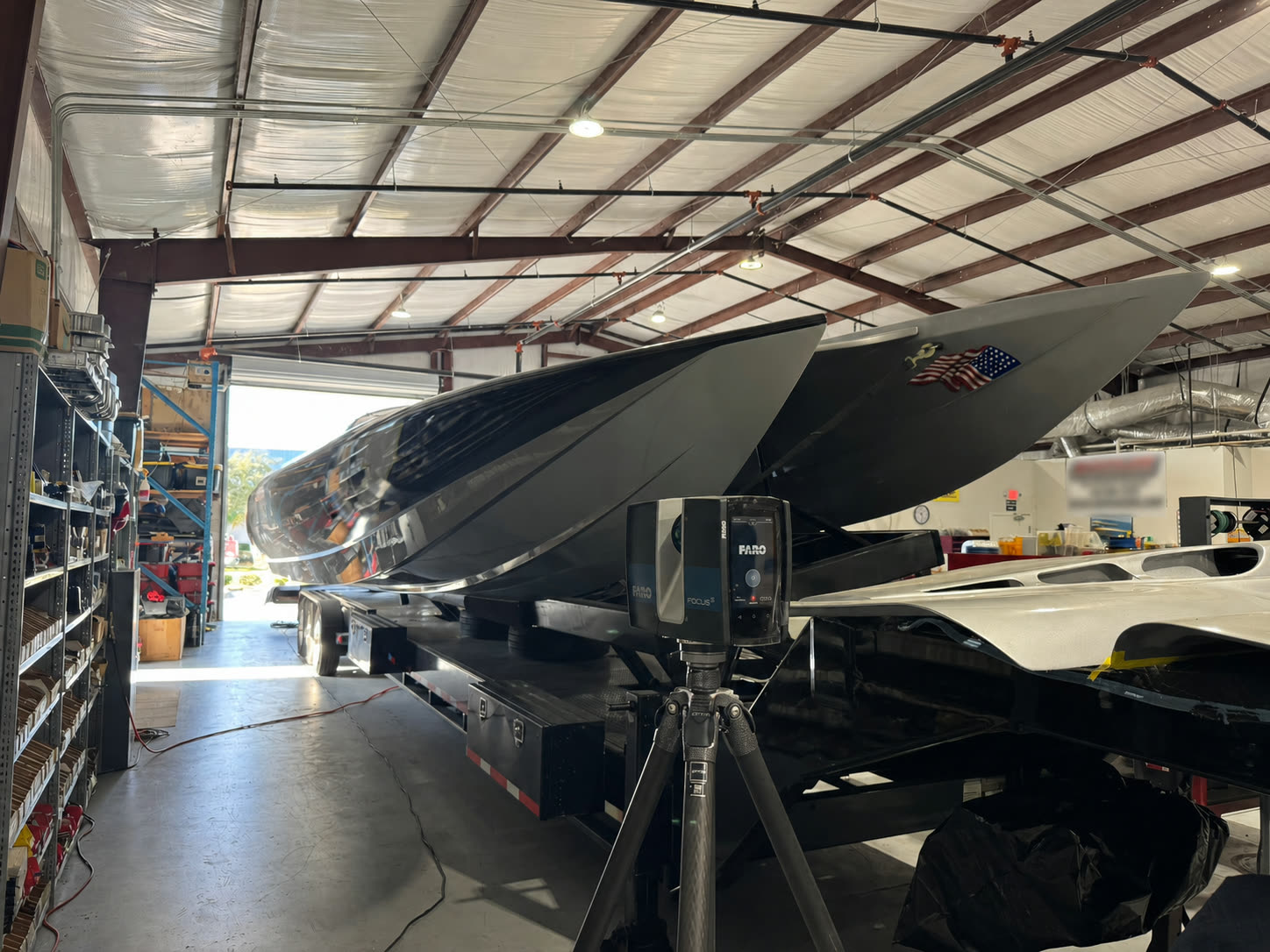Laser scanner on a tripod capturing a race catamaran hull in the shop